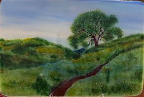 Fused glass and hand-painted landscape scene with a tree and rolling hills 