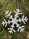White snowflake ornament on a branch of a pine tree